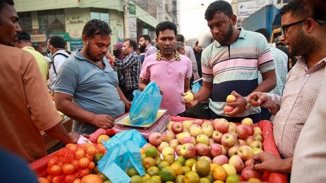 একটি ভ্যান থেকে আপেল ও কমলা কিনছেন কয়েকজন 