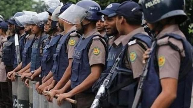 কয়েকজন পুলিশ সদস্য ইউনিফর্মের ওপর ভেস্ট পরে শিল্ড নিয়ে দাঁড়িয়ে আছেন
